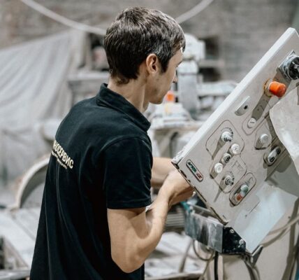 Pracownik obsługujący maszynę w zakładzie produkcyjnym